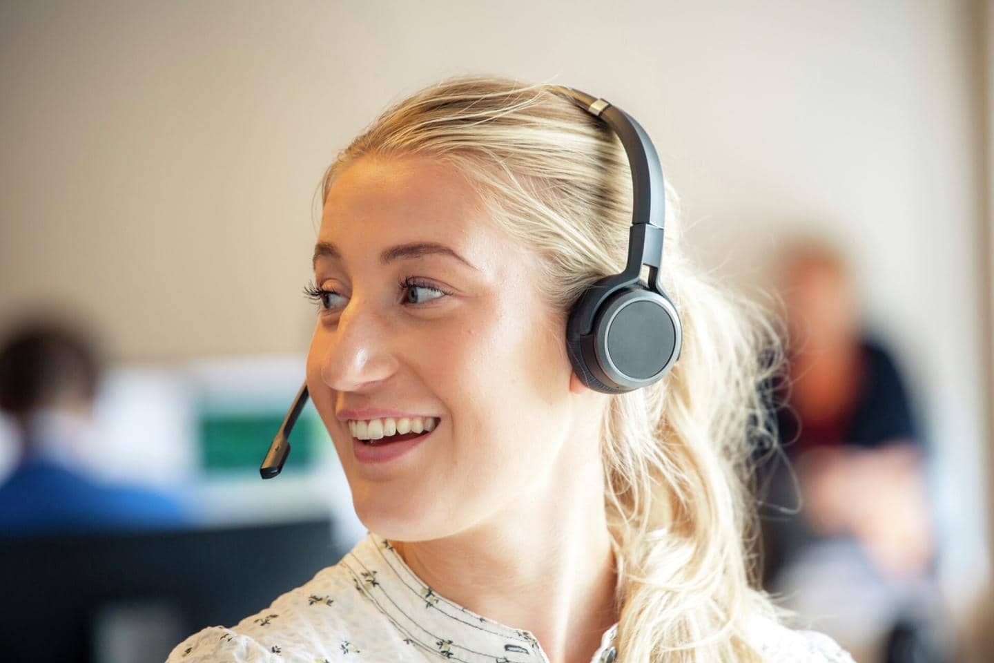 Kvinde med headset smiler og kigger til venstre
