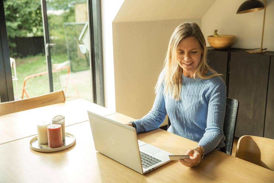Kvinde, der sidder ved et bord med en computer