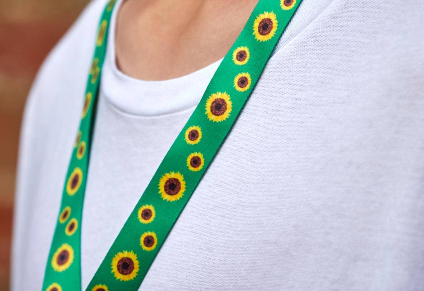 Person med solsikkeprogrammet nøglehænger om halsen og hvid t-shirt, fotografi