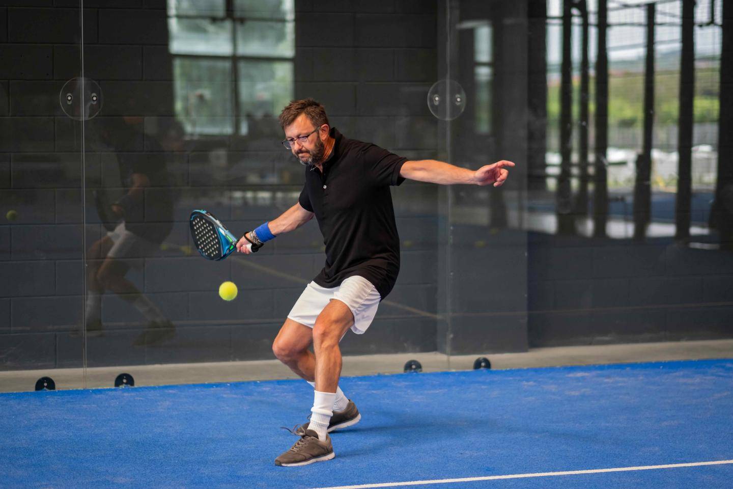 Mand spiller padel på blå bane